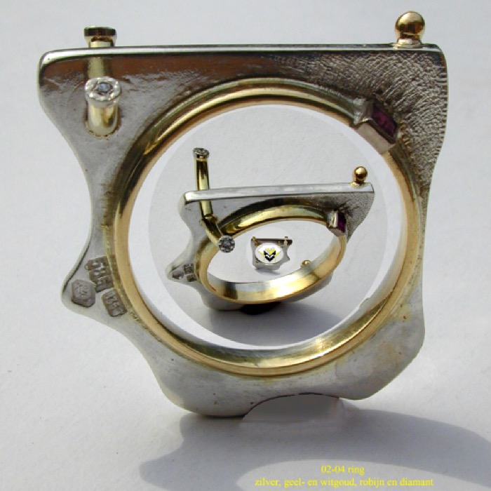 02-04 : ring
zilver, geel- en witgoud, robijn (carré) + 2x diamant 
2x 1e piqué 0.015 ct. tot. 10,3 gr.   € 250,-